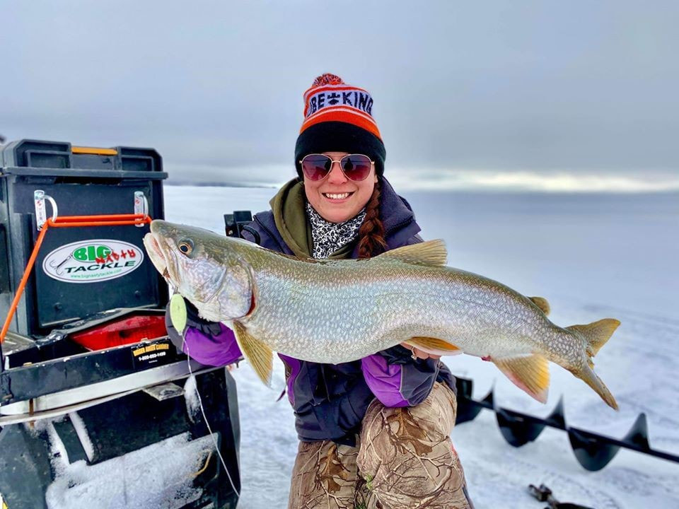 Woman holding large lake trout caught while ice fishing with Big Nasty Tackle.